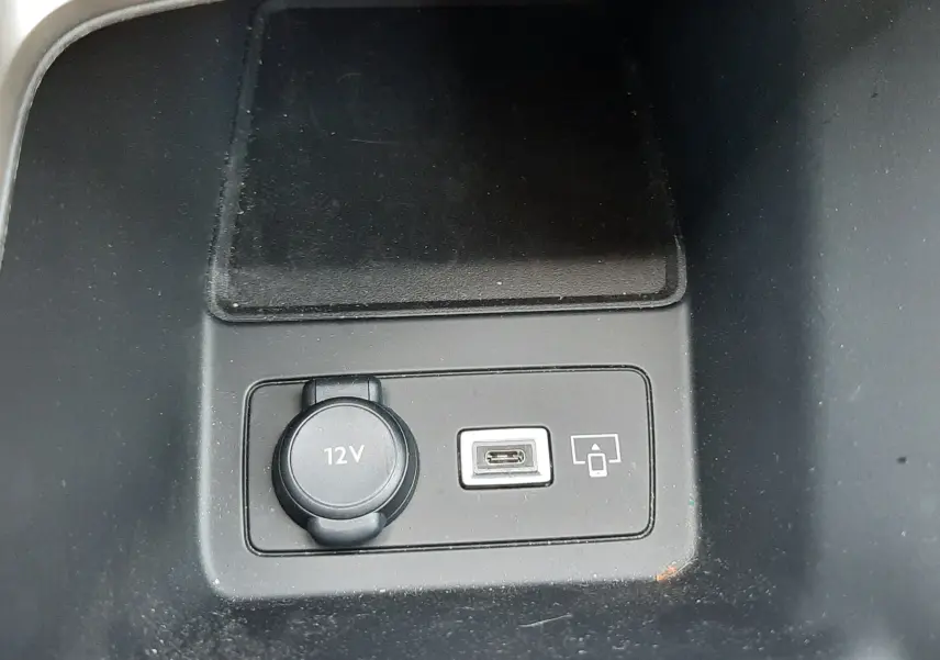 Prise 12V et port USB-C en gros plan sur la console centrale d’une Peugeot 408 gris selenium 2024.