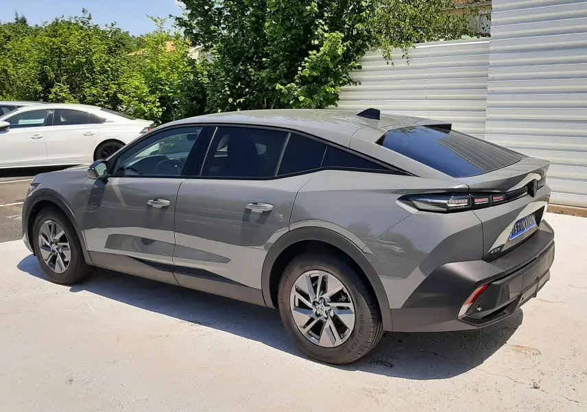 Peugeot 408 Hybrid gris selenium vue 3/4 arrière côté droit, avec toit noir et feux arrière LED distinctifs.