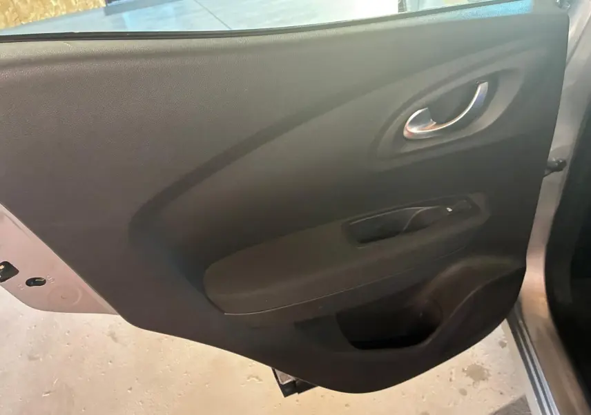 Vue intérieure de la porte arrière droite du Renault Kadjar gris, avec poignée argentée et commande de vitre noire.
