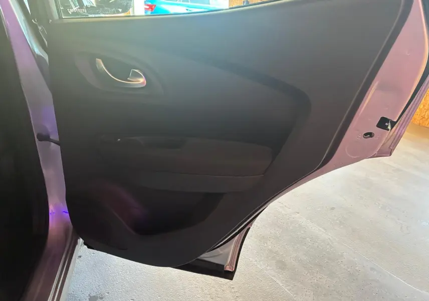 Vue rapprochée de la porte arrière gauche ouverte du Renault Kadjar gris, montrant la garniture intérieure noire.