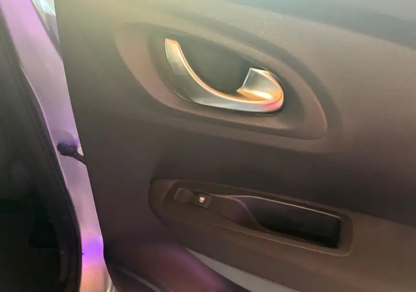 Poignée intérieure et commande de lève-vitre côté gauche d’une Renault Kadjar gris, finition tissu noir.