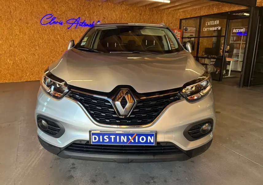 Vue de face d'un Renault Kadjar gris 2020, mettant en valeur la calandre noire et les phares LED dans un showroom.