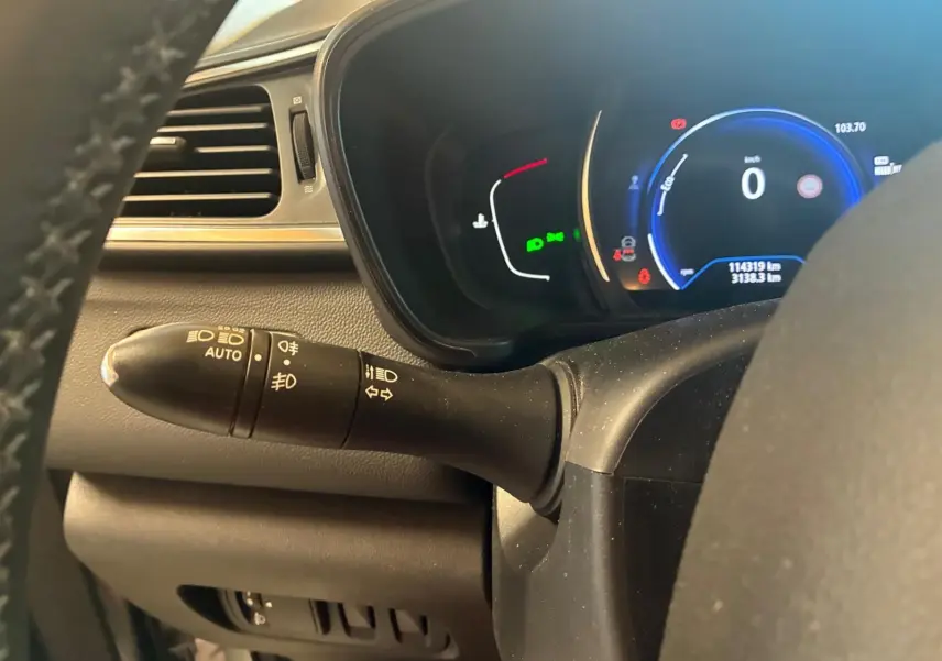 Vue rapprochée du combiné d'instruments et du commodo d'éclairage dans un Renault Kadjar gris, tableau de bord numérique allumé.