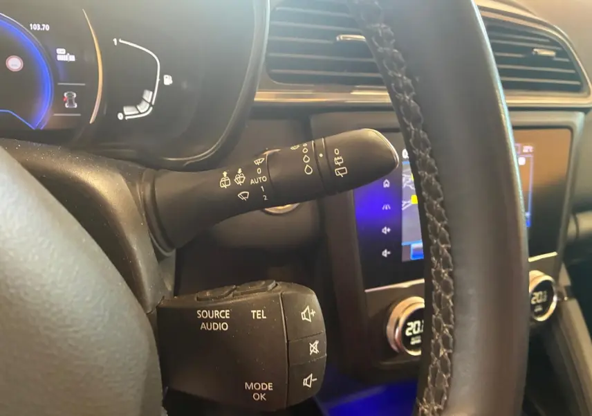 Gros plan sur le volant et la commande multifonction du Renault Kadjar gris, tableau de bord et écran tactile en arrière-plan.