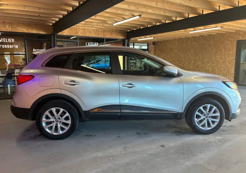 Vue de profil côté gauche d'un Renault Kadjar gris 2020 stationné en intérieur avec jantes alliage visibles.