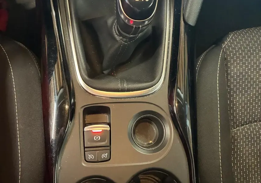 Vue de dessus du levier de vitesses manuel noir et console centrale du Renault Kadjar gris, avec porte-gobelets et bouton frein à main électrique.