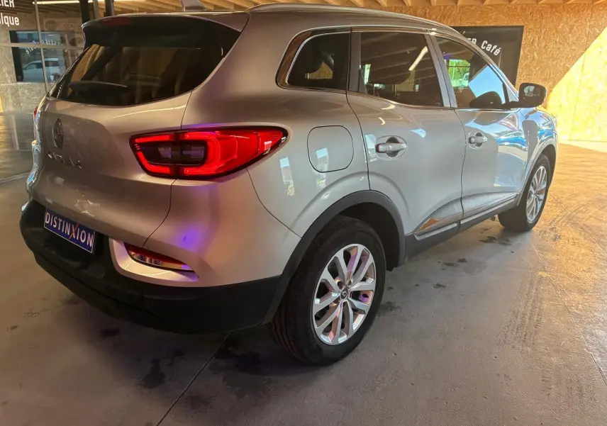 Vue 3/4 arrière droit du Renault Kadjar gris 2020 avec feux arrière allumés dans un garage intérieur.