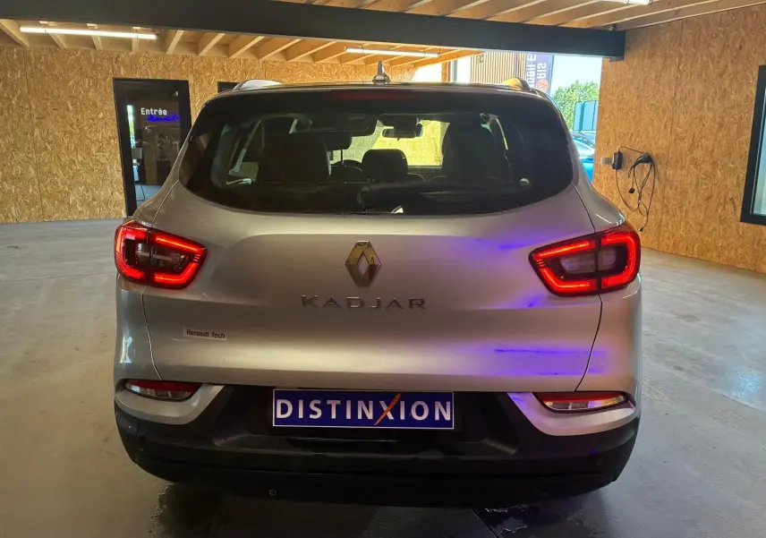 Vue arrière du Renault Kadjar gris 2020 avec feux allumés et logo distinctif dans un garage.
