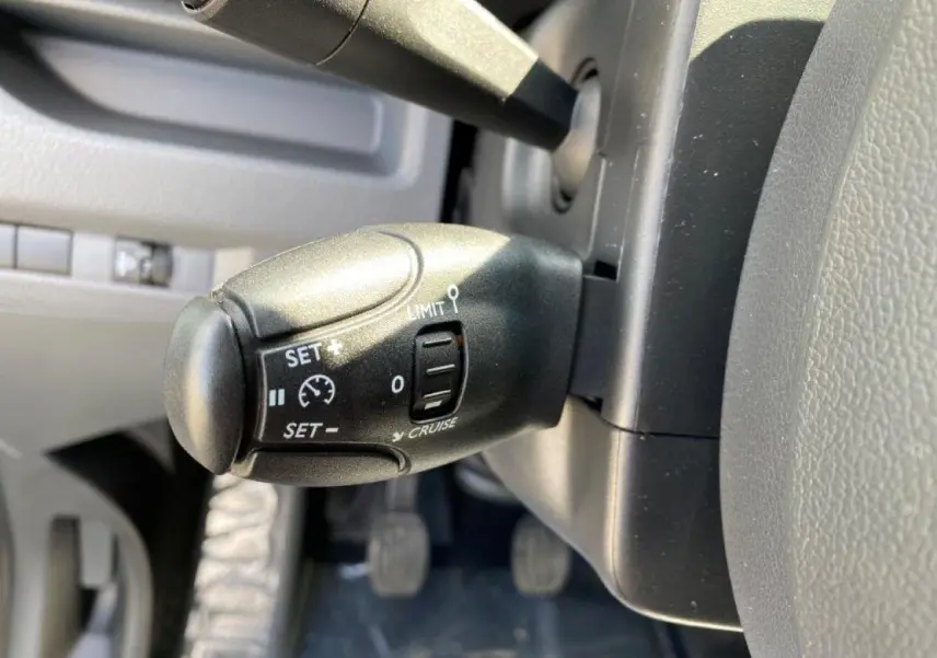 Gros plan sur la commande du régulateur de vitesse noire, côté gauche du volant du Peugeot Expert Fourgon blanc 2023.