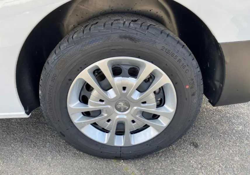 Gros plan sur la roue avant droite du Peugeot Expert Fourgon blanc 2023 avec jante en alliage et logo lion central.