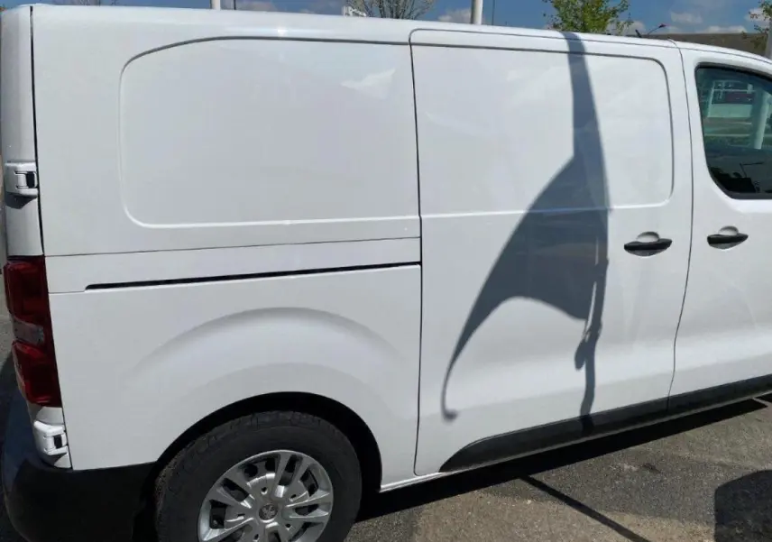 Vue latérale droite d'un Peugeot Expert Fourgon blanc 2023 avec porte coulissante et jante acier.