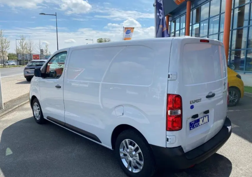 Vue 3/4 arrière droite d'un fourgon blanc Peugeot Expert avec porte latérale coulissante et jantes alliage.