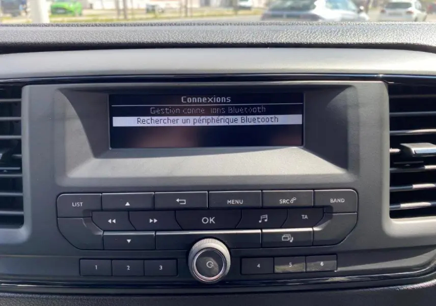 Gros plan sur la console centrale du Peugeot Expert Fourgon blanc 2023, affichant la recherche Bluetooth sur l'écran digital.