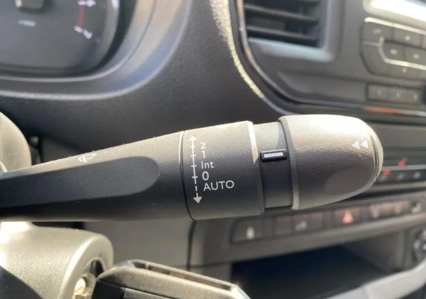 Gros plan sur la commande d'essuie-glace automatique du Peugeot Expert Fourgon blanc, tableau de bord en arrière-plan.