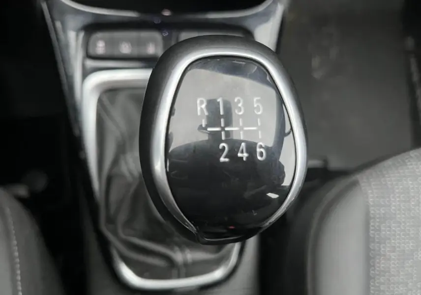 Gros plan sur le levier de vitesses manuel noir de l'Opel Crossland 1.2i Turbo Edition, intérieur sombre.
