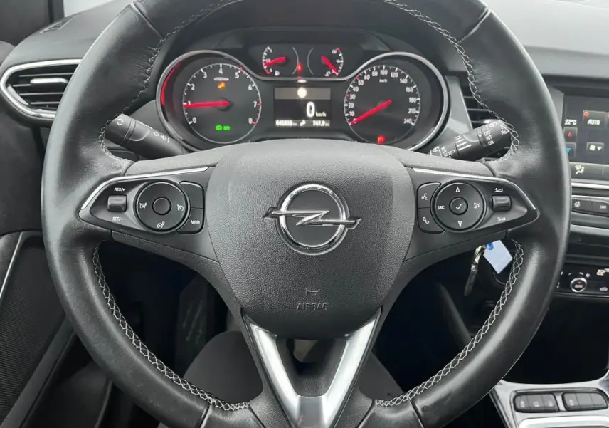 Vue rapprochée du volant noir de l'Opel Crossland 2021 avec commandes intégrées et tableau de bord visible.