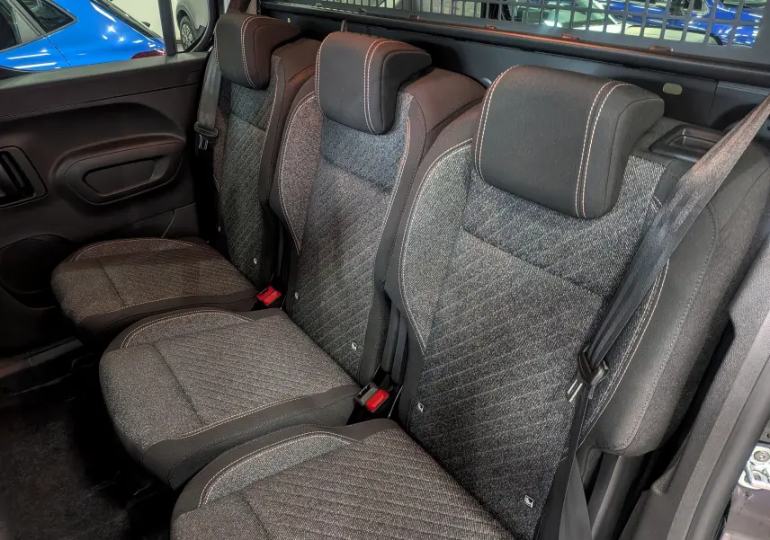 Vue intérieure côté droit des sièges arrière en tissu gris du Peugeot Rifter noir, avec appuie-têtes et ceintures visibles.