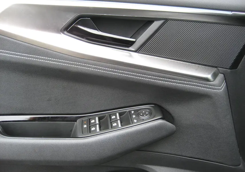 Détail de la porte côté gauche du Renault Austral gris 2025, montrant les commandes des vitres et la poignée intérieure.