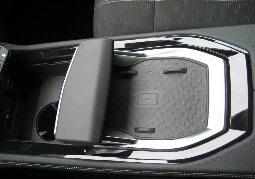 Gros plan intérieur sur la console centrale noire du Renault Austral gris, mettant en valeur le repose-bras et le chargeur sans fil.