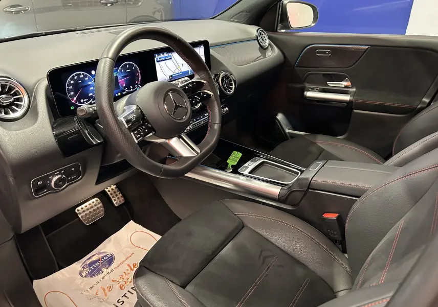 Intérieur côté conducteur du Mercedes GLA 200 D AMG Line 2024, avec tableau de bord numérique et sellerie cuir noir à surpiqûres rouges.