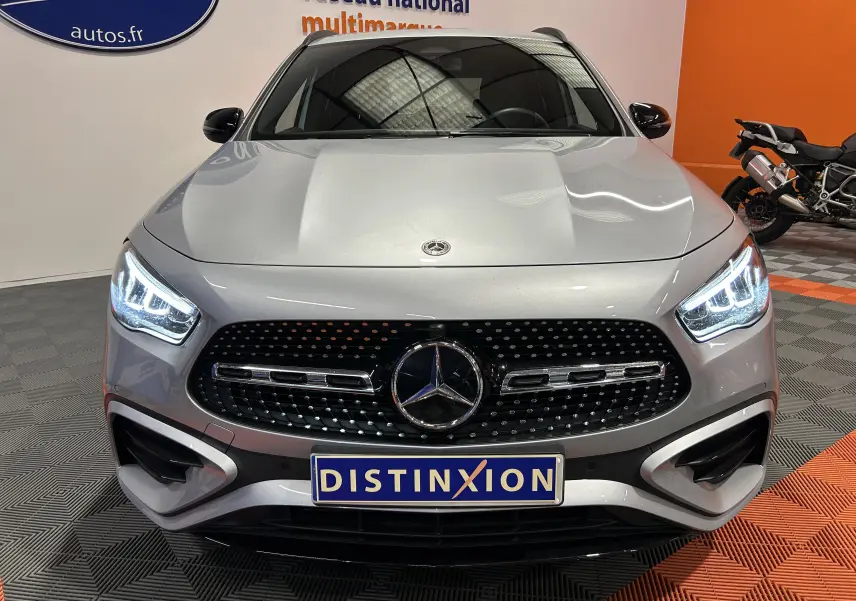 Vue frontale d'une Mercedes GLA 200 D AMG Line 2024 en argent High-tech avec calandre noire à motifs étoilés et phares LED allumés.
