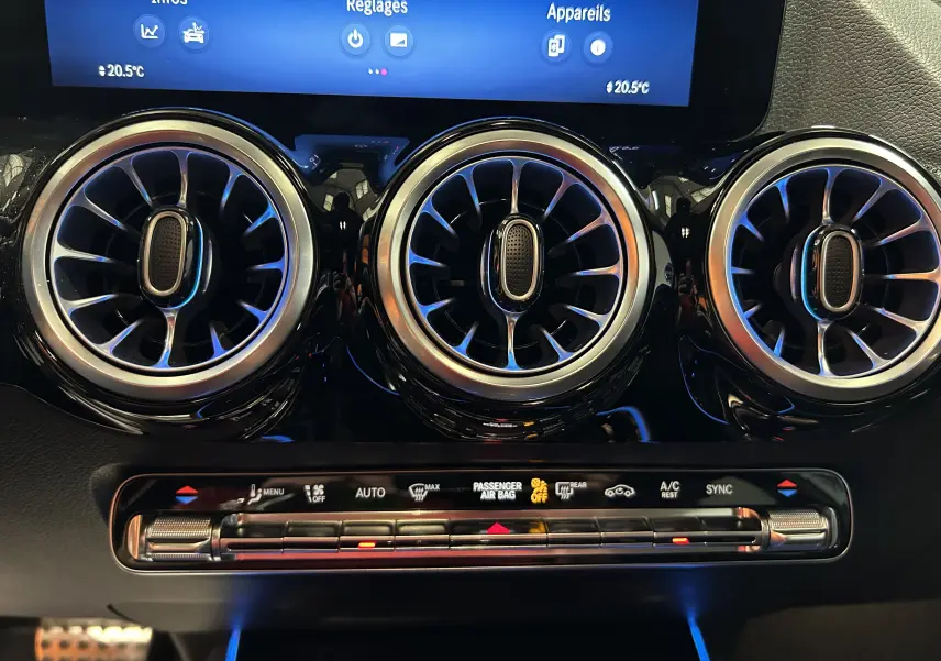 Détail du tableau de bord du Mercedes GLA 200 D AMG Line 2024 montrant les aérateurs ronds chromés et la commande de climatisation automatique.