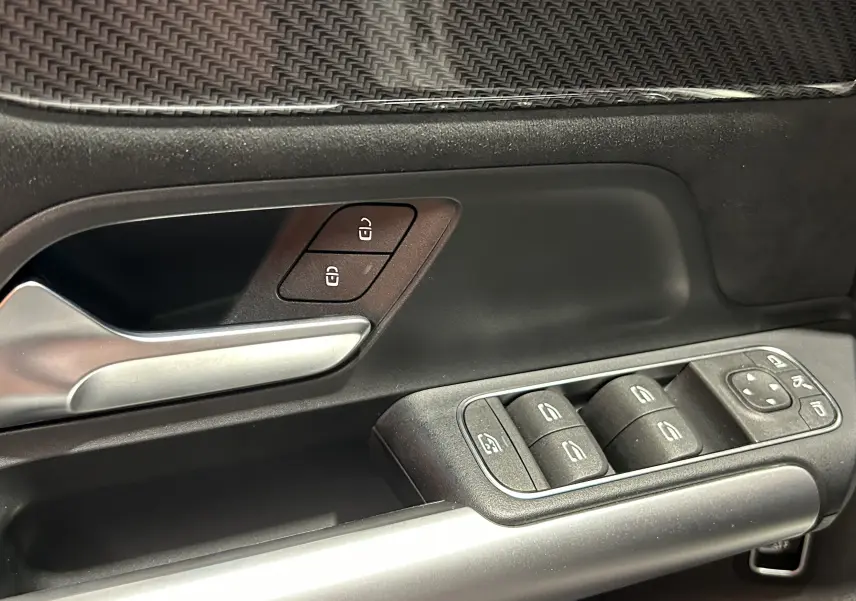Gros plan sur la porte côté gauche de la Mercedes GLA 200 D AMG Line 2024, avec commandes de vitres et poignée argentée.