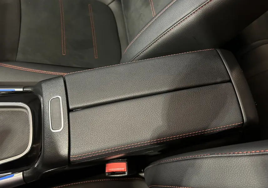 Gros plan sur l'accoudoir central en cuir noir avec surpiqûres rouges dans le Mercedes GLA 200 D AMG Line 2024.