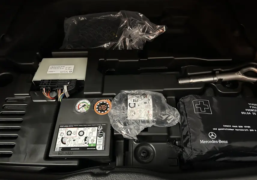Vue rapprochée du compartiment de secours du Mercedes GLA 200 D AMG Line 2024, avec kit de réparation et outils.
