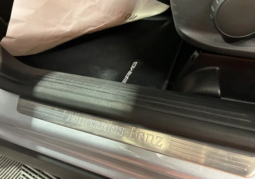 Gros plan sur la baguette de seuil de porte argentée Mercedes-Benz et tapis AMG noir dans un GLA 200 D AMG Line 2024.