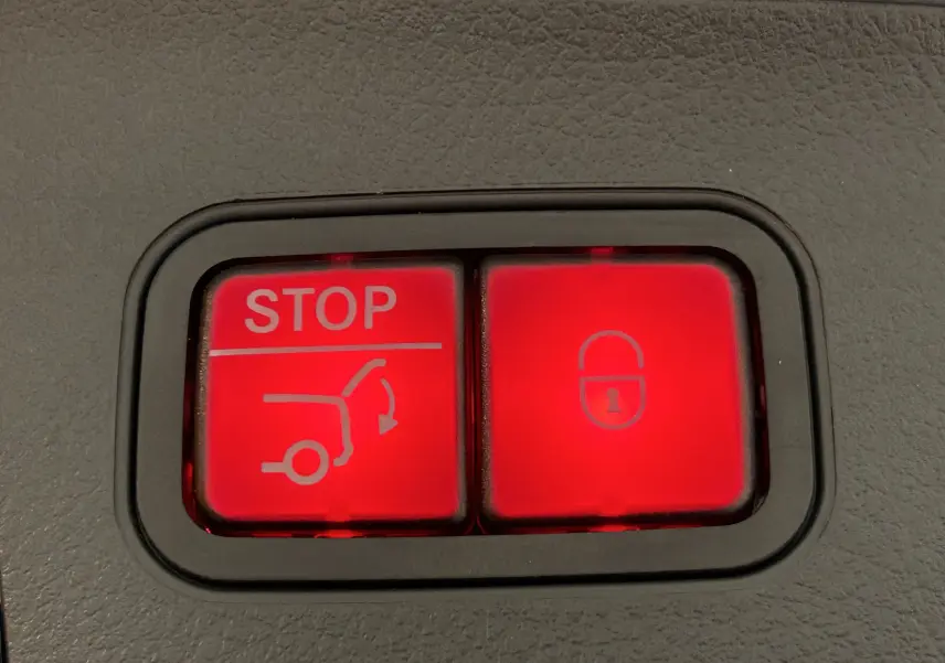 Boutons rouges d'ouverture et de verrouillage du hayon sur la console intérieure d'une Mercedes GLA argent High-tech 2024.