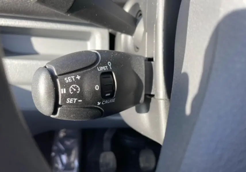 Gros plan sur la commande de régulateur de vitesse à gauche du volant du Peugeot Expert Fourgon blanc banquise 2023.