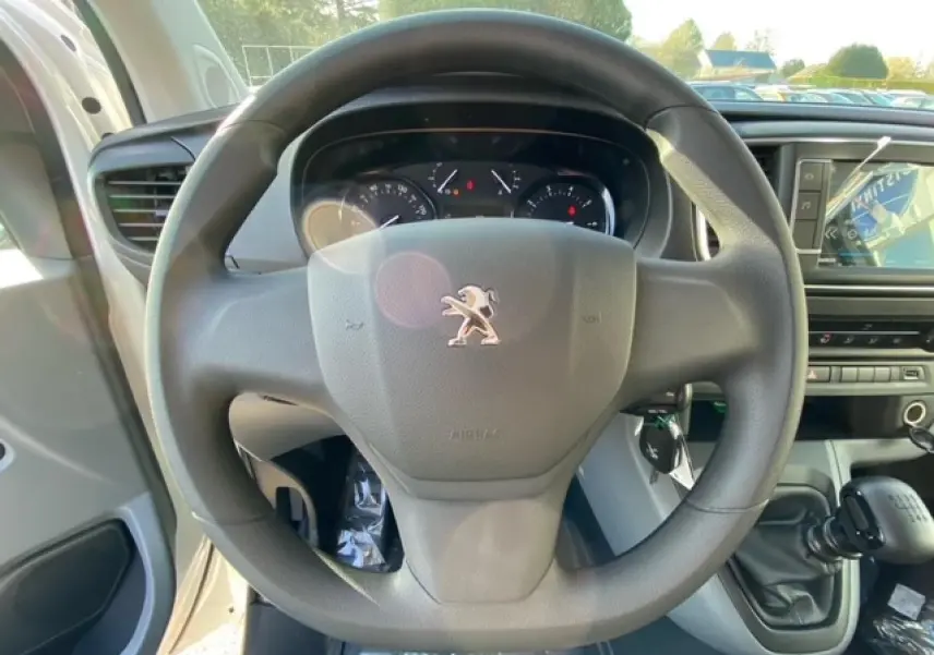 Vue rapprochée du volant Peugeot Expert Fourgon blanc banquise 2023 avec tableau de bord et levier de vitesses manuel visible.