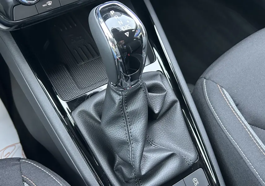 Gros plan sur la commande de boîte automatique cuir noir du Skoda Kamiq 2025, intérieur tissu gris avec surpiqûres contrastées.
