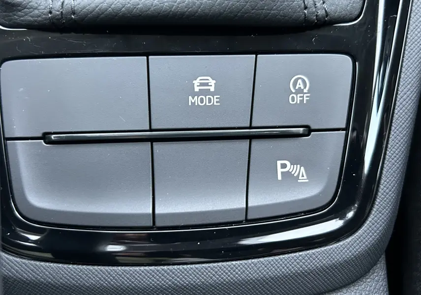 Gros plan sur les boutons de commande du mode de conduite et assistance au stationnement dans une Skoda Kamiq gris argent 2025.