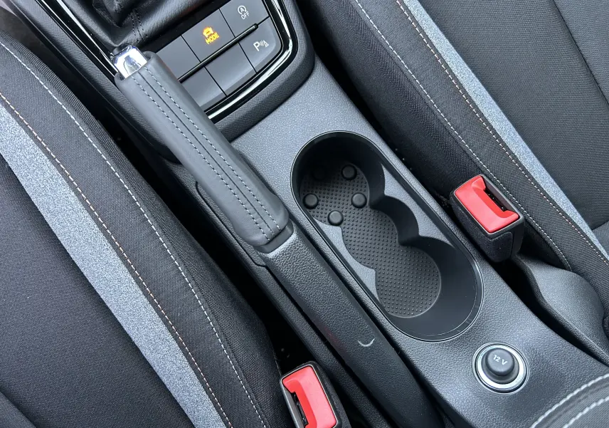 Détail intérieur de la console centrale grise avec frein à main cuir, porte-gobelets et boutons de commande sur Skoda Kamiq 2025.