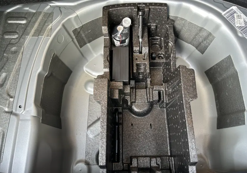 Vue en plongée du coffre à outils et rangement sous le plancher du coffre du Skoda Kamiq gris argent métal 2025.