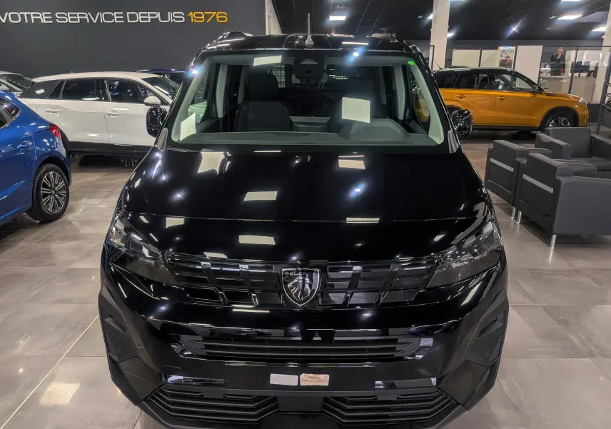 Vue de face d’un Peugeot Rifter noir 2025 dans un showroom, mettant en valeur sa calandre et ses phares modernes.