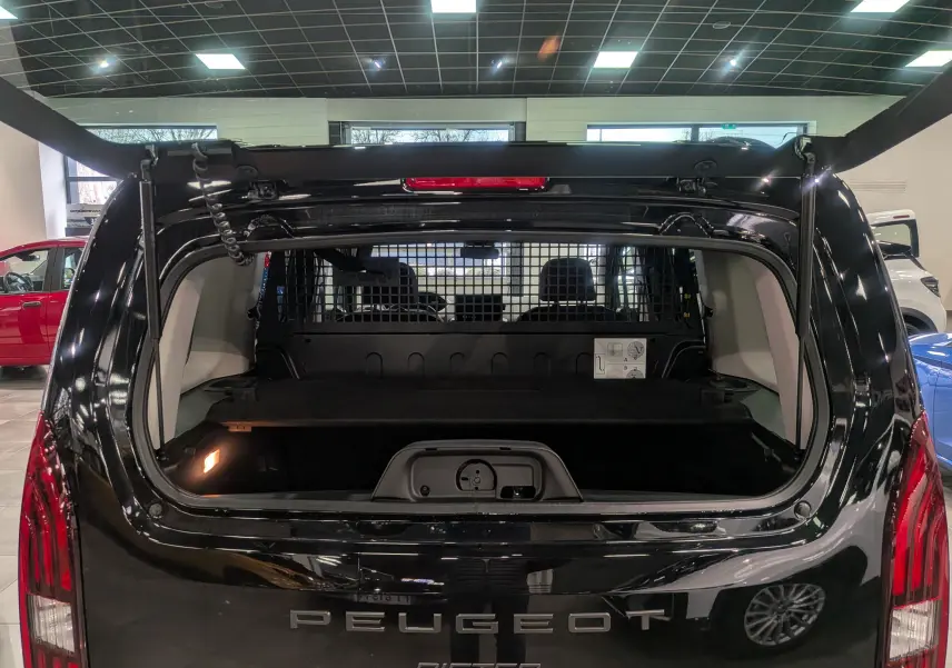 Vue arrière ouverte du coffre d’un Peugeot Rifter noir 2025, avec séparation grillagée visible à l’intérieur.