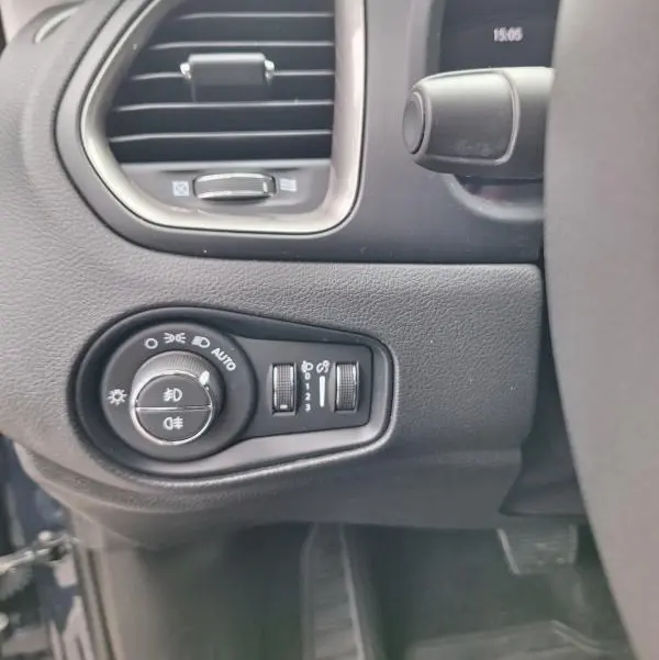 Détail du tableau de bord côté gauche d’un Jeep Renegade bleu 2024, avec commandes des phares et ventilation.