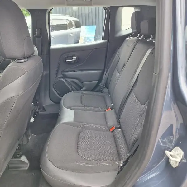 Vue intérieure côté arrière droit du Jeep Renegade bleu 2024, montrant les sièges arrière en tissu noir et la portière ouverte.