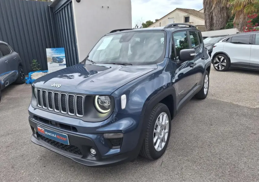 Jeep Renegade bleu vue 3/4 avant droit, avec barres de toit et jantes alliage 17 pouces visibles.