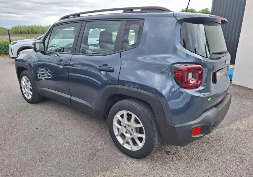 Vue 3/4 arrière droite d’un Jeep Renegade bleu 2024 avec barres de toit et jantes alliage 17 pouces.