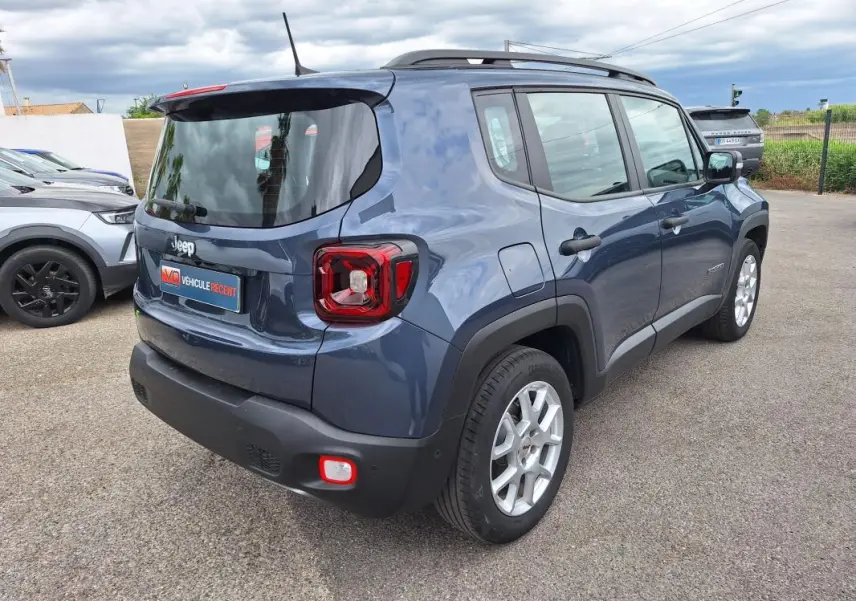 Jeep Renegade bleu en vue 3/4 arrière droit, avec barres de toit et jantes alliage 17 pouces visibles.
