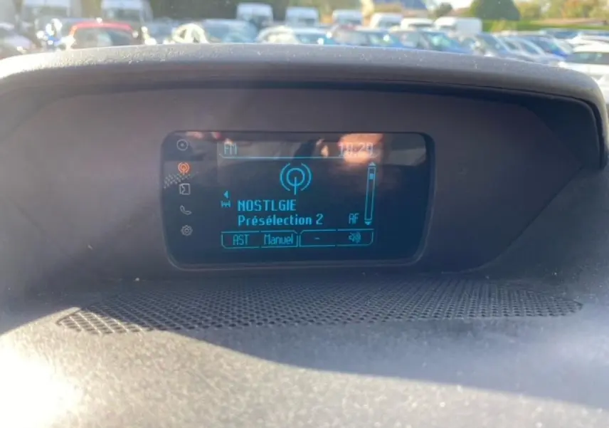 Écran central du tableau de bord du Ford Transit Fourgon L3H2 2015 affichant une station radio en mode manuel.