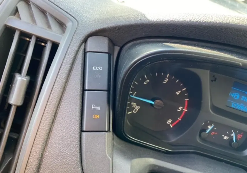 Gros plan sur le tableau de bord du Ford Transit Fourgon L3H2 2015, montrant le compte-tours et les boutons ECO et radar de stationnement activé.
