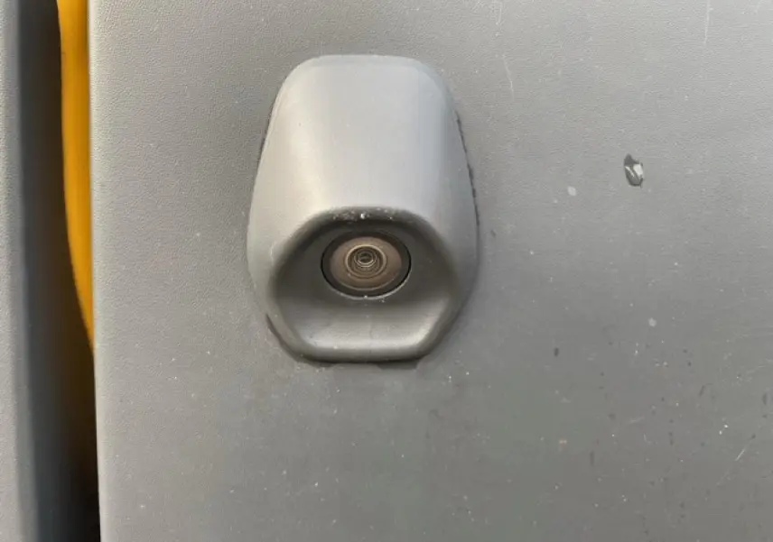 Gros plan sur la caméra de recul intégrée à la porte arrière grise du Ford Transit Fourgon orange L3H2 2015.