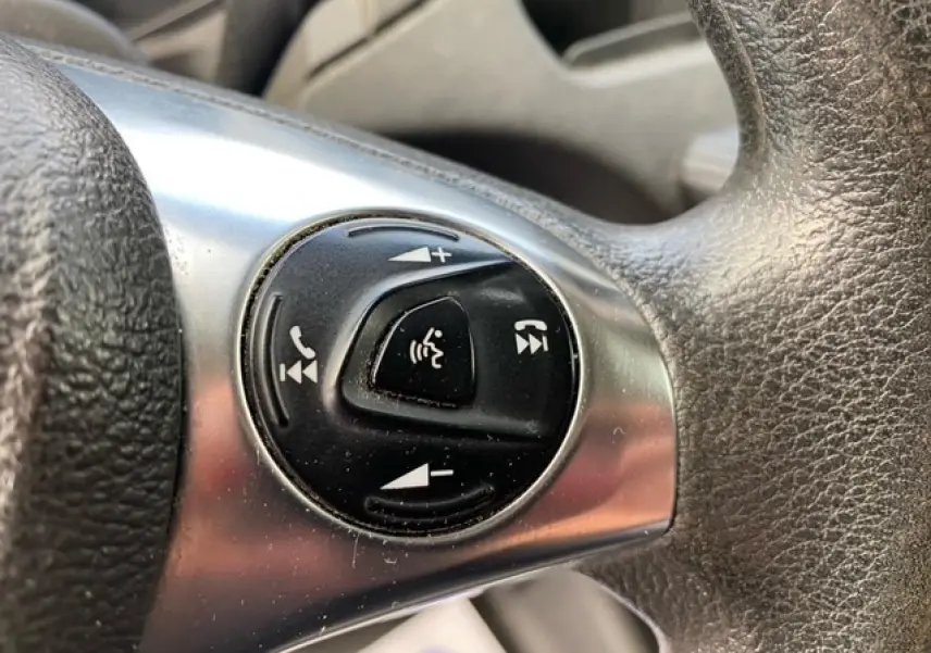 Gros plan sur les commandes audio et téléphone au volant du Ford Transit Fourgon L3H2 2015, intérieur noir.