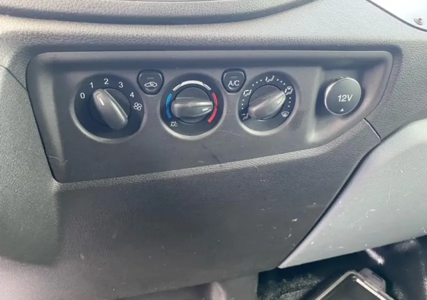 Détail du tableau de commande de climatisation et prise 12V dans un Ford Transit Fourgon L3H2 2015 noir.
