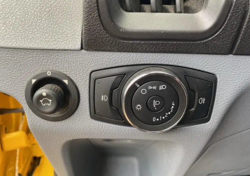 Gros plan sur les commandes d'éclairage et réglage du tableau de bord du Ford Transit Fourgon orange 2015.